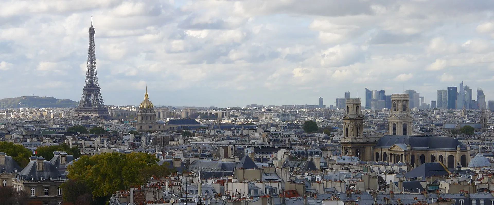 Paris rooftops under a cloudy sky, with the Eiffel Tower, the gilded dome of Les Invalides and Saint-Sulpice